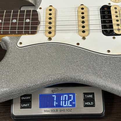 Silver electric guitar on a digital scale displaying weight.