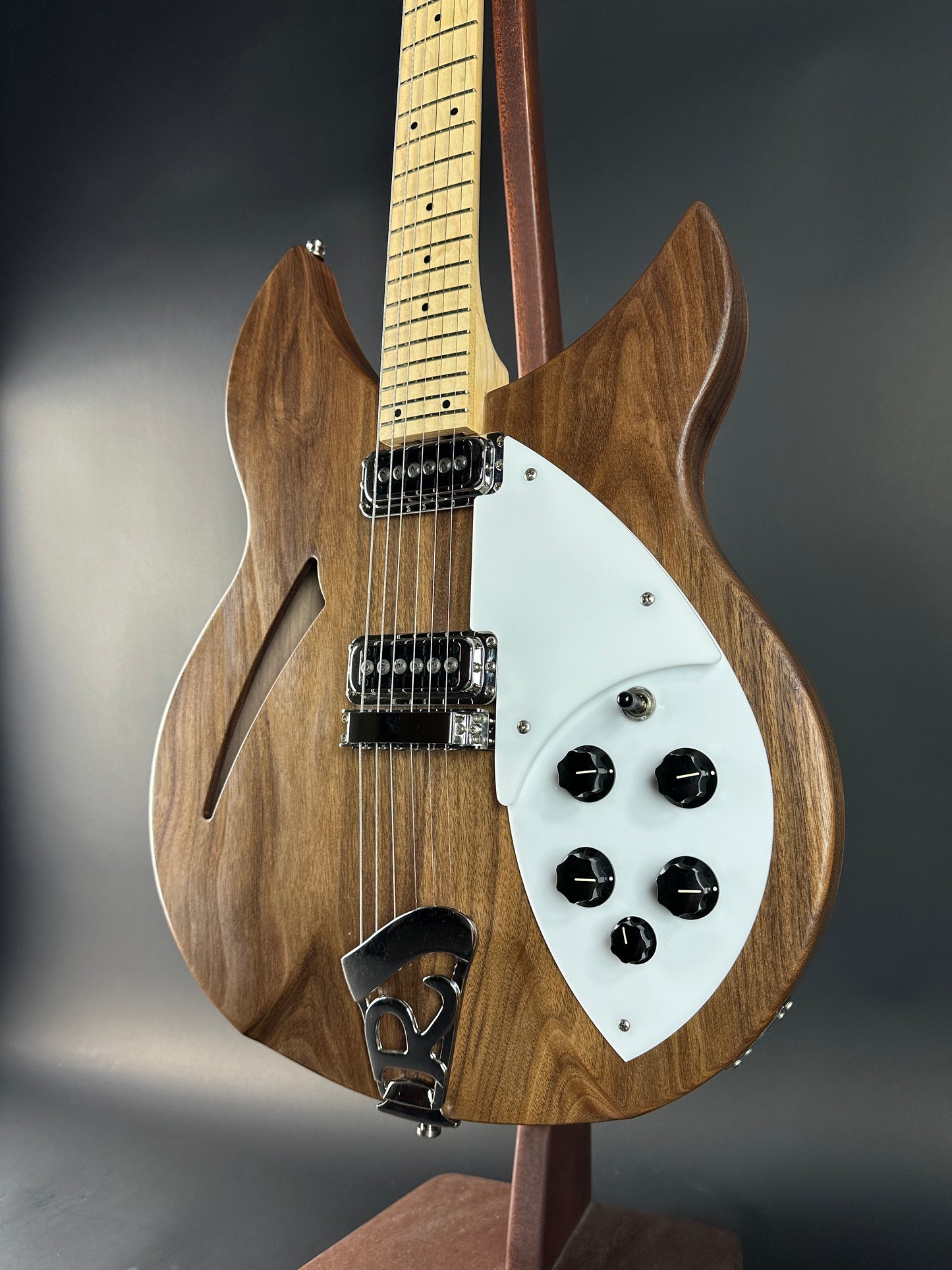 Wooden electric guitar with a white pickguard on a dark background