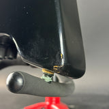 Close-up of a black metal object with a red tool in the background