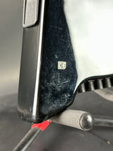 Close-up of a car seat belt buckle with visible wear and a logo on a metallic background.