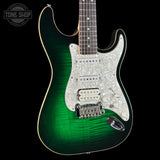 A classic electric guitar with a green-to-brown flamed maple finish, featuring a white mother-of-pearl pickguard and chrome hardware, shown against a solid black background.