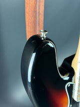 Close-up of a guitar's headstock with a black finish and wooden fretboard.