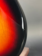 Close-up of a guitar with a sunburst finish on a neutral background