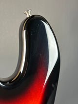 Close-up of a guitar neck with a red and black finish on a gray background