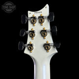 Close-up of a guitar headstock with tuning pegs on a black background, featuring 'Tone Shop' branding.