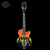 A custom electric guitar with a black body, bright orange upper bout, and yellow and black flame decals on the lower bout. The guitar features white mother-of-pearl inlays on the fretboard and headstock, red knobs, and a chrome tailpiece.