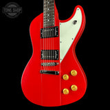 Red electric guitar with a white pickguard on a black background, featuring the Tone Shop logo.