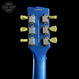 Close-up of a blue guitar headstock with tuning pegs on a black background, featuring 'Tone Shop' branding.