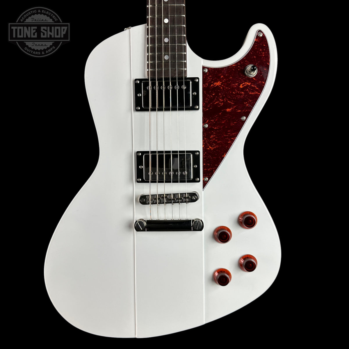 White electric guitar with a red pickguard on a black background, featuring the Tone Shop logo.