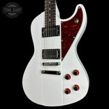White electric guitar with a red pickguard on a black background, featuring the Tone Shop logo.