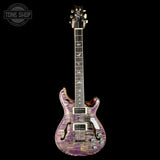 Electric guitar with a purple flame finish on a black background, featuring the Tone Shop logo.