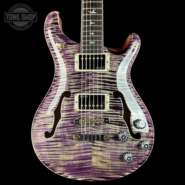 Purple and white electric guitar with a visible brand logo in the corner.
