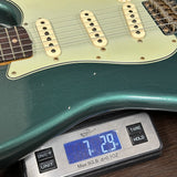 Teal electric guitar on a digital scale displaying weight