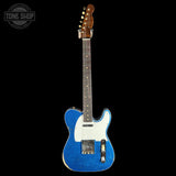 Blue electric guitar with a white pickguard on a black background, featuring 'Tone Shop' branding.