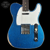 Blue electric guitar with white pickguard on a black background, featuring 'Tone Shop' logo.