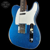Blue electric guitar with white pickguard on a black background, featuring 'Tone Shop' logo.