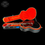 Guitar in an open case with a visible brand logo on a black background