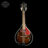 A Thetford mandolin with a glossy brown wooden body, red and black patterned pickguard, and black headstock, shown against a solid black background with a Tone Shop watermark in the top left.
