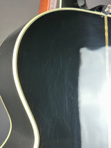 Close-up of a black acoustic guitar with visible wood grain texture.
