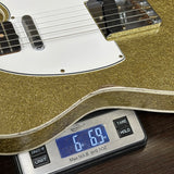 Gold electric guitar on a digital scale displaying weight