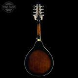 A mandolin shown from the back against a solid black background, featuring a glossy dark brown sunburst finish, white binding, and silver metal tuning hardware. A circular 'TONE SHOP' watermark is visible in the top-left corner.