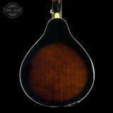 Close-up of the back of a mandolin showing a dark brown sunburst finish and a white edge trim, set against a solid black background with a Tone Shop watermark in the top left.