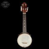 A wooden banjo with a white drumhead and silver metal hardware, photographed against a solid black background. A Tone Shop watermark is visible in the top-left corner.