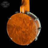 Close-up of the back of a wooden banjo against a black background, showing the glossy brown wood body and silver metal hardware. A Tone Shop watermark is visible in the upper left corner.