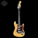 A Fender Stratocaster electric guitar with a natural wood finish body, dark fretboard, and red glitter pickguard, shown against a solid black background with a Tone Shop watermark in the top-left corner.