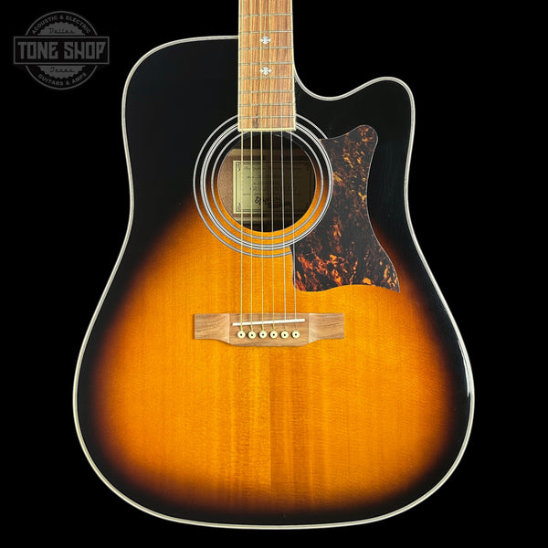 Acoustic guitar with a sunburst finish on a black background, featuring the Tone Shop logo.