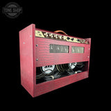 A red crocodile-embossed guitar amplifier head with a gold control panel and dual rear speakers, shown against a solid black background with a Tone Shop watermark in the top-left corner.