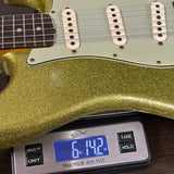 Gold glittery electric guitar on a digital scale displaying weight.