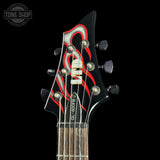 Close-up of a guitar headstock with red and black design on a black background, featuring the Tone Shop logo.