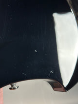 Close-up of a black guitar headstock with chrome finish