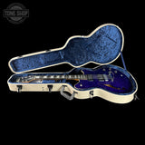 Blue electric guitar in an open case with 'Tone Shop' logo.