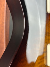 Close-up detail of a glossy dark brown wooden curved trim or edge against a reflective light surface.