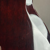 Close-up of a glossy dark reddish-brown wooden surface with visible scratches and a white protective film partially peeled back.