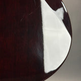 Close-up of a glossy dark reddish-brown wooden surface with visible scratches and a bright white reflection, against a light gray background.
