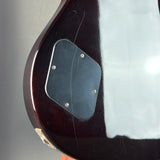 Close-up of the lower bout body of an electric guitar, showing a glossy dark reddish-brown wood finish, a black pickguard, and a white protective film covering the right side.