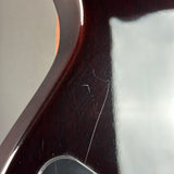 Close-up of a glossy dark reddish-brown wooden surface with visible scratches and reflections, likely part of a guitar body.