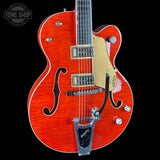 A red-orange flamed maple electric guitar with a gold pickguard, chrome hardware, and a black pickguard, shown against a black background with a Tone Shop watermark in the top left corner.