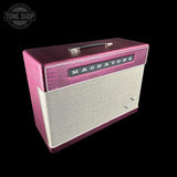 A vintage-style Magnitone guitar amplifier cabinet shown at an angle against a solid black background. The cabinet features a textured magenta-pink top and sides, a cream-colored front grille cloth, and a black nameplate with silver lettering.