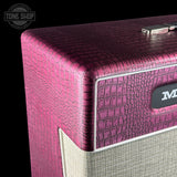 Close-up of a guitar amplifier corner featuring a textured magenta-pink crocodile-patterned top and side, with a beige fabric grille below and a visible partial 'M' logo badge. A Tone Shop watermark appears in the upper left.
