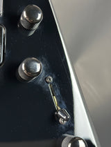 Close-up of a guitar control panel with knobs and a switch.