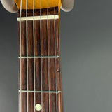 Close-up of a guitar neck with frets and strings on a gray background