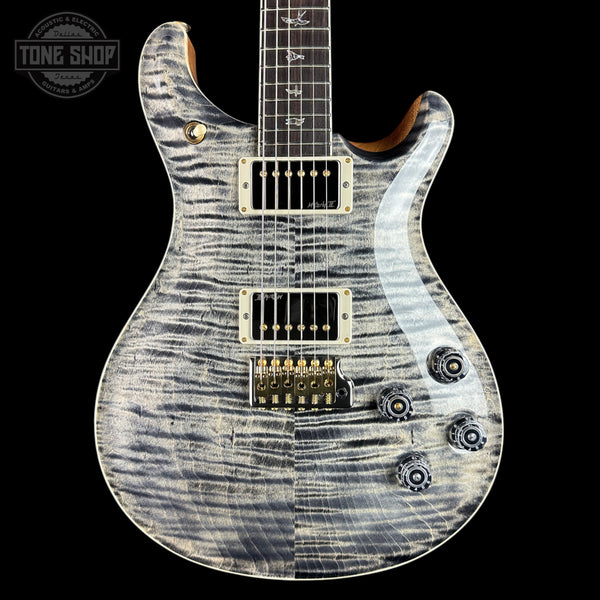 A Prussik electric guitar with a silver and black flamed maple top, shown against a solid black background. The guitar features gold hardware and a white pickguard, with a Tone Shop watermark in the upper left corner.