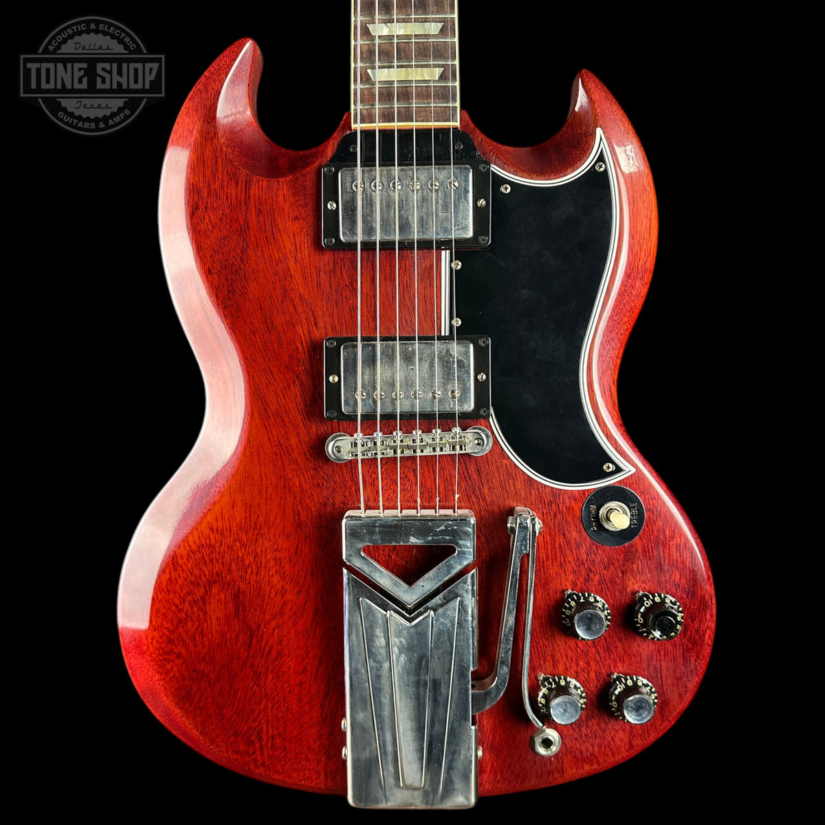 Red electric guitar with a black pickguard on a black background, featuring the Tone Shop logo.
