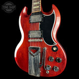 Red electric guitar with a black pickguard on a black background, featuring the Tone Shop logo.