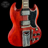 Red electric guitar with a black pickguard on a black background, featuring the Tone Shop logo.