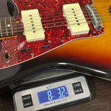 Guitar on a digital scale displaying weight, with a close-up view of the guitar's body and neck.
